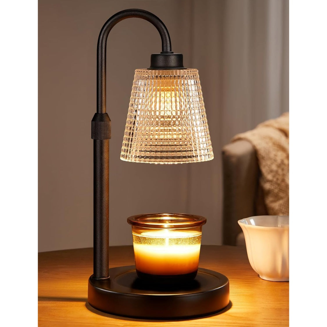 Lumbra Pro candle warmer lamp glowing over a candle on a wooden side table